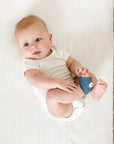 Owlet Dream Sock - Baba fehér bodyban ágyneműn, lábán okos babafigyelő zokni, kiságyban fekve