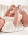 Baba rózsaszín okos zokniban, fehér bodyban, kiságyban fekszik