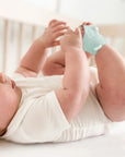 Baba menta színű okos zokniban, fehér bodyban, kiságyban fekve