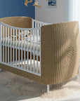 Modern rattan babaágy fehér rácsokkal, világos babaszobában, prémium gyerekbútor