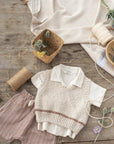 Bébi pamut mellény, rövid ujjú ing és csíkos rövidnadrág, természetes színekben, rusztikus háttéren.