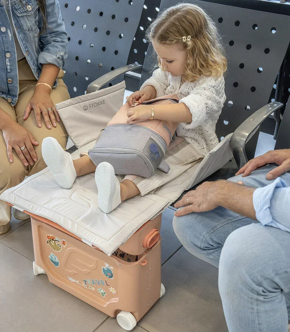 Kislány JetKids utazóbőrönddel, lehajtható ággyal, repülőtéri váróban ül