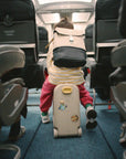 Gyerek jetkids bőröndön ül repülőgép utasterében, hátizsákkal, utazási gyerek kiegészítő