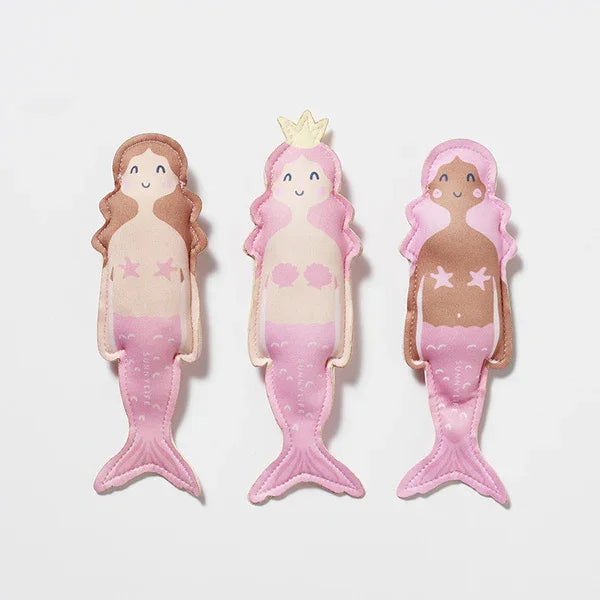 Három rózsaszín sellő plüss figura, vidám arccal, gyerekjáték, fehér háttéren.