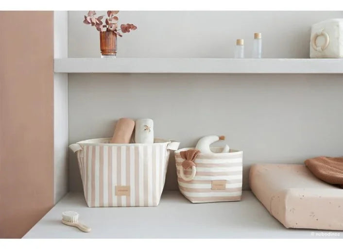 Bézs csíkos textil játéktartó kosarak babaszobában, természetes dekorációval.